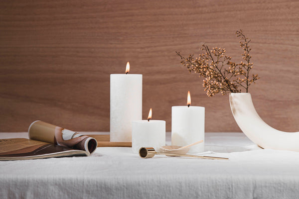 White Living Light Candles Pillar candles on white table cloth with brown wooden background