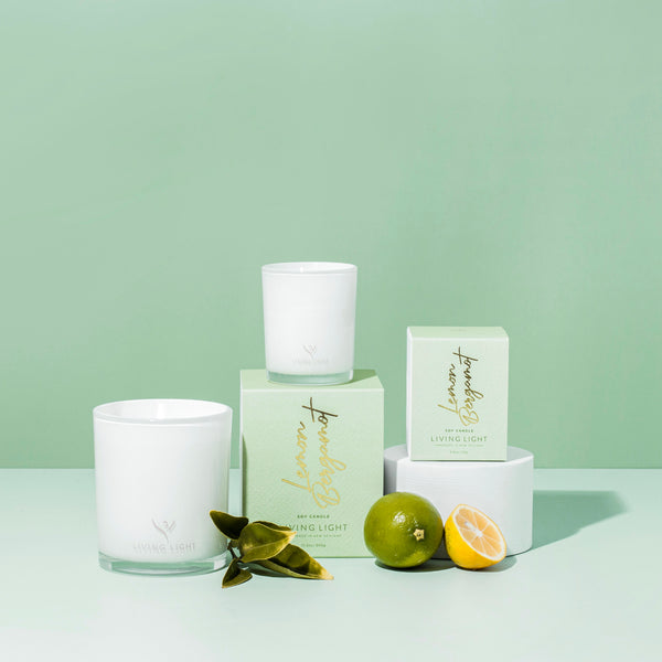 lemon bergamot living light soy candle, handmade in Nz. set in glass packaging, lemon and limes placed in front of the candles.