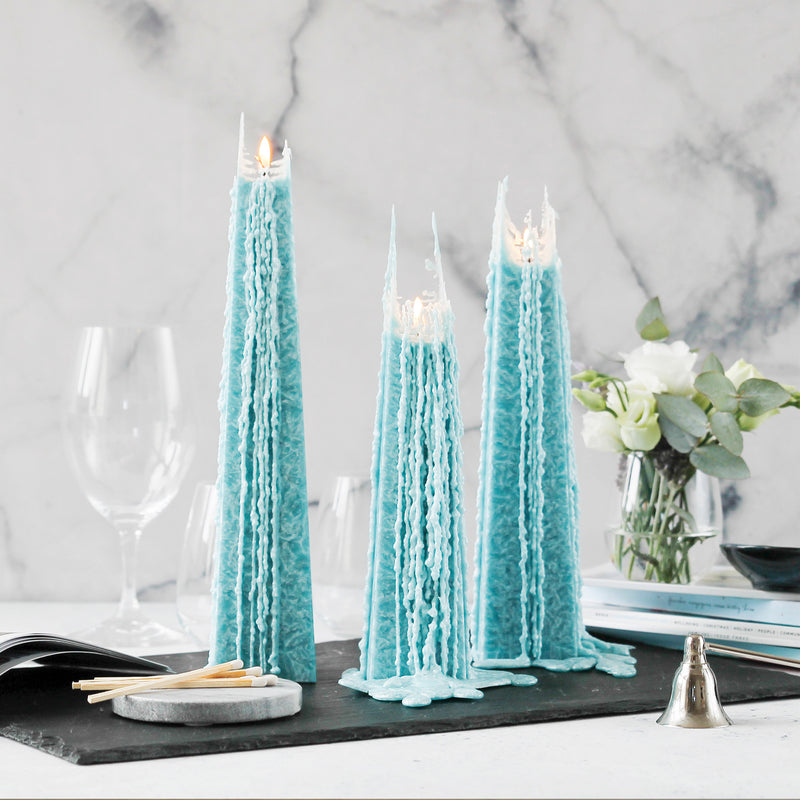 Living Light Ocean Sage Icicle Candles burning with signature drip effect, styled on a marble dining table with flowers, wine glasses, and matches.