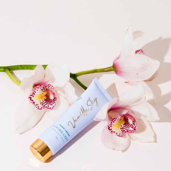 vanilla hand cream in blue and gold packaging lying on top of flowers | living light 